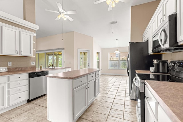 kitchen with a center island, appliances with stainless steel finishes, a ceiling fan, white cabinetry, and lofted ceiling