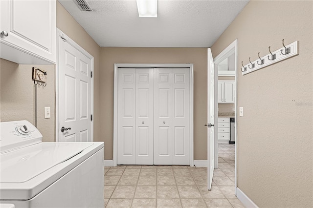 clothes washing area featuring a textured ceiling, washer / dryer, and cabinets