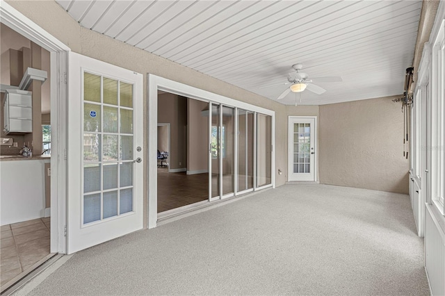 unfurnished sunroom with wooden ceiling, a healthy amount of sunlight, and ceiling fan