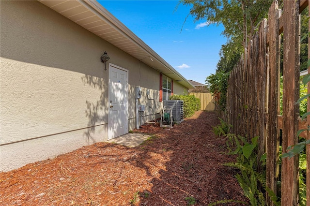 view of home's exterior with fence, central AC unit, and stucco siding