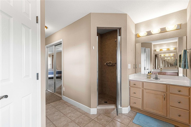 bathroom with baseboards, a textured ceiling, vanity, tile patterned floors, and a stall shower