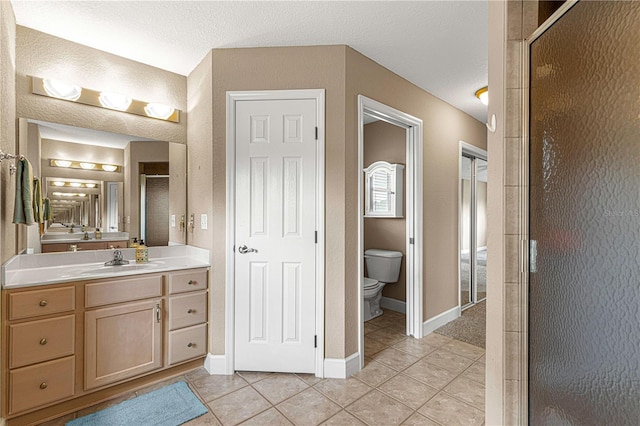full bath with vanity, tile patterned flooring, toilet, a stall shower, and baseboards