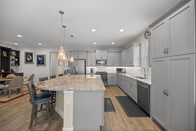 kitchen featuring gray cabinets, stainless steel appliances, light hardwood / wood-style flooring, and a kitchen island