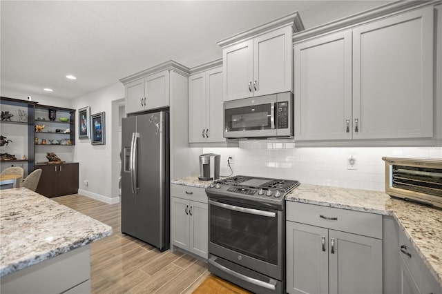 kitchen with decorative backsplash, stainless steel appliances, gray cabinetry, and light hardwood / wood-style floors