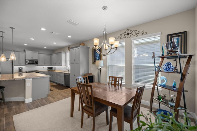 dining room with dark hardwood / wood-style flooring, sink, and a notable chandelier