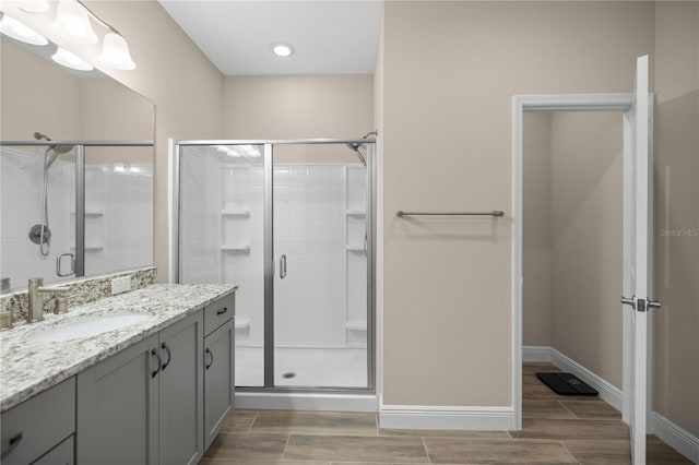 bathroom featuring hardwood / wood-style floors, a shower with door, and vanity