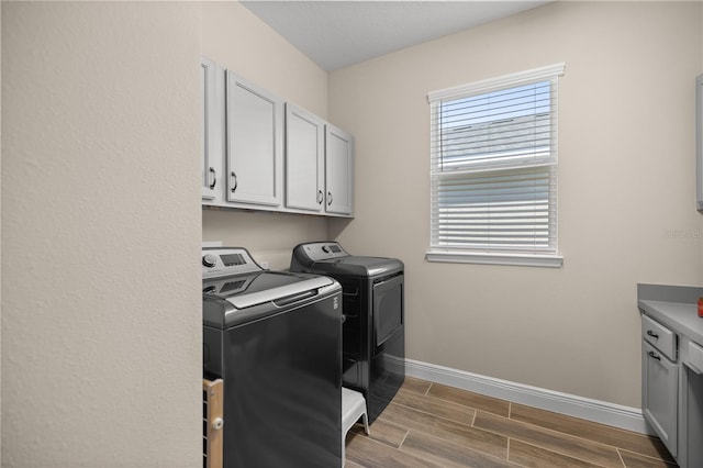 laundry area with wood-type flooring, cabinets, and independent washer and dryer