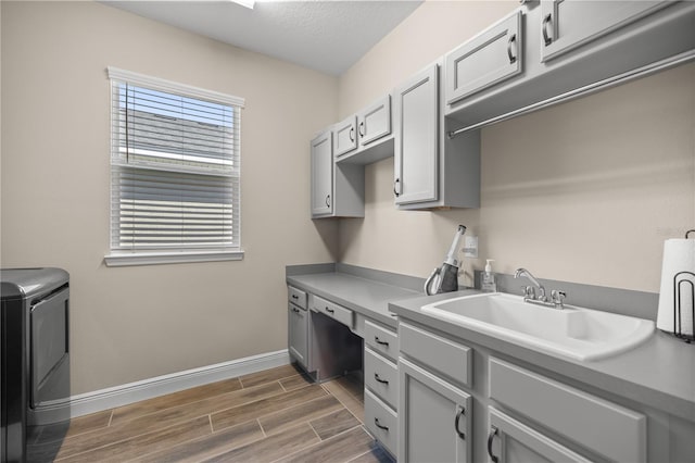 clothes washing area with sink, a textured ceiling, dark wood-type flooring, washer / clothes dryer, and cabinets