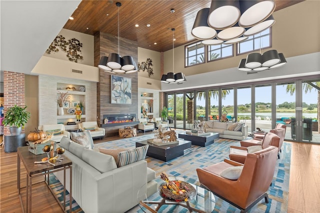 living room featuring a towering ceiling, a fireplace, wooden ceiling, hardwood / wood-style floors, and a chandelier