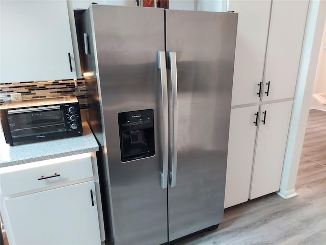 kitchen with light hardwood / wood-style flooring, tasteful backsplash, stainless steel fridge with ice dispenser, and white cabinets