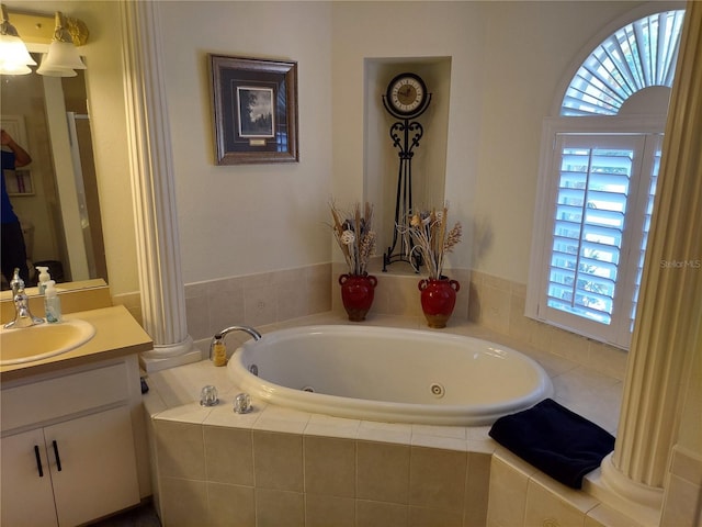 bathroom featuring tiled tub and vanity