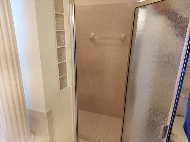 bathroom with a shower with door and toilet