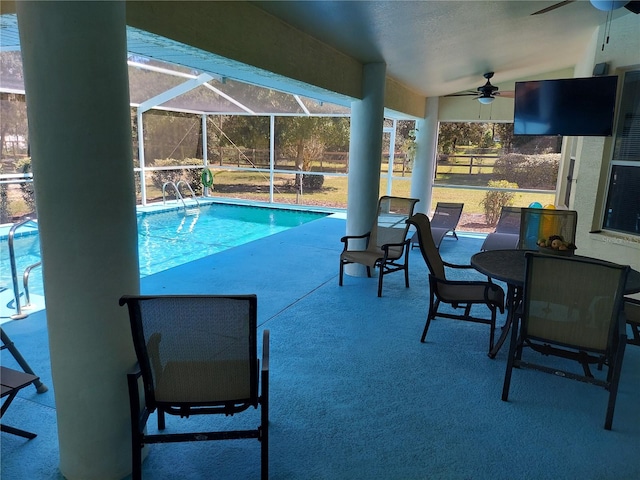 view of swimming pool featuring glass enclosure, ceiling fan, and a patio