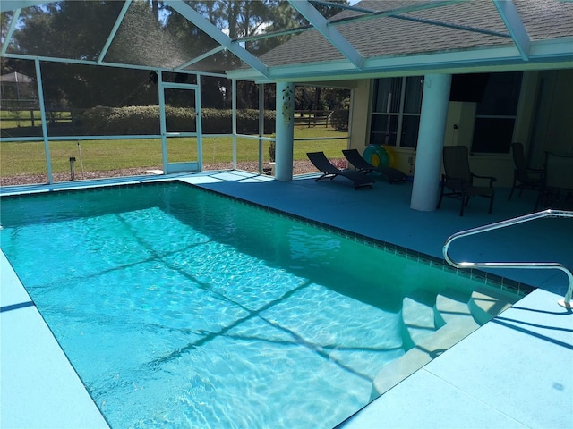 view of swimming pool with glass enclosure, a lawn, and a patio area