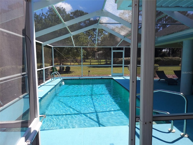 view of pool featuring glass enclosure, a patio, and a lawn