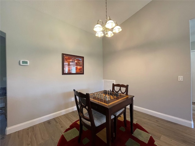 dining space with wood-type flooring, a chandelier, and high vaulted ceiling