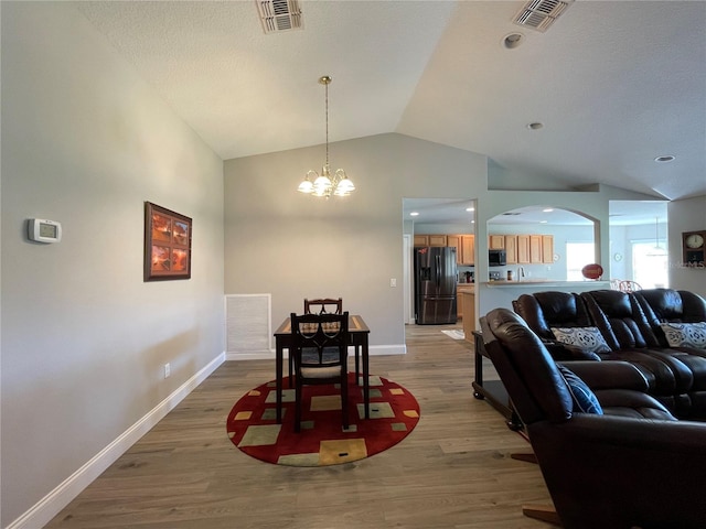 dining area featuring light hardwood / wood-style floors, vaulted ceiling, and a chandelier