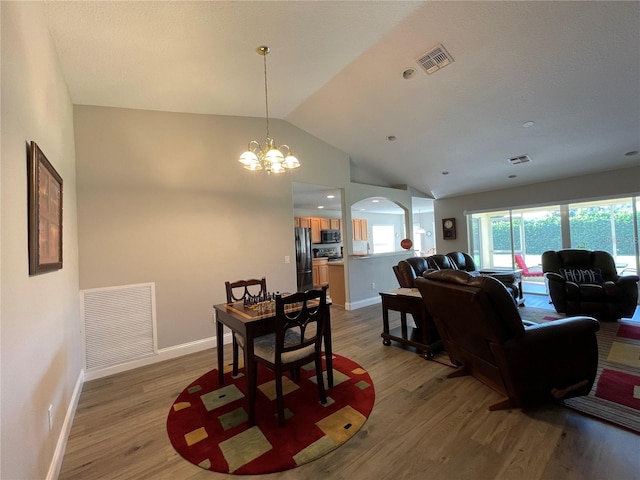 dining room featuring lofted ceiling, a notable chandelier, and hardwood / wood-style floors