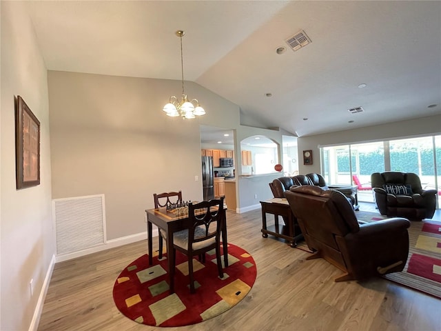 dining room featuring light wood-type flooring, a notable chandelier, and lofted ceiling