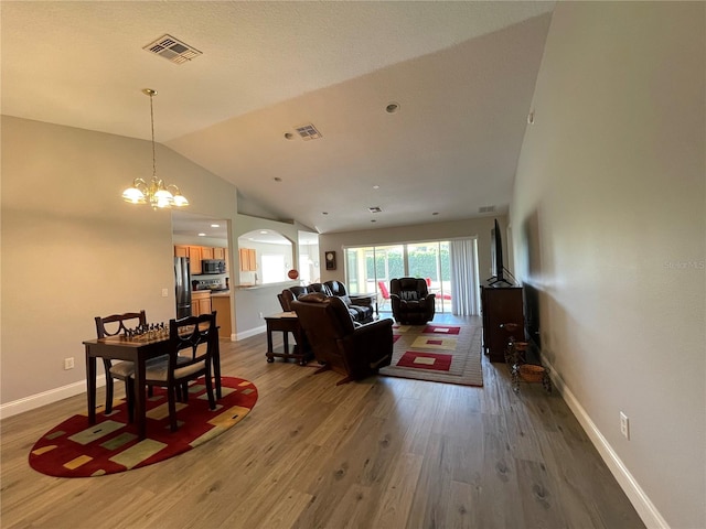 living room featuring lofted ceiling, hardwood / wood-style floors, and a notable chandelier