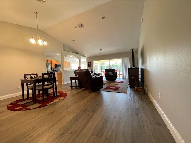 living room featuring a notable chandelier, vaulted ceiling, and dark hardwood / wood-style flooring