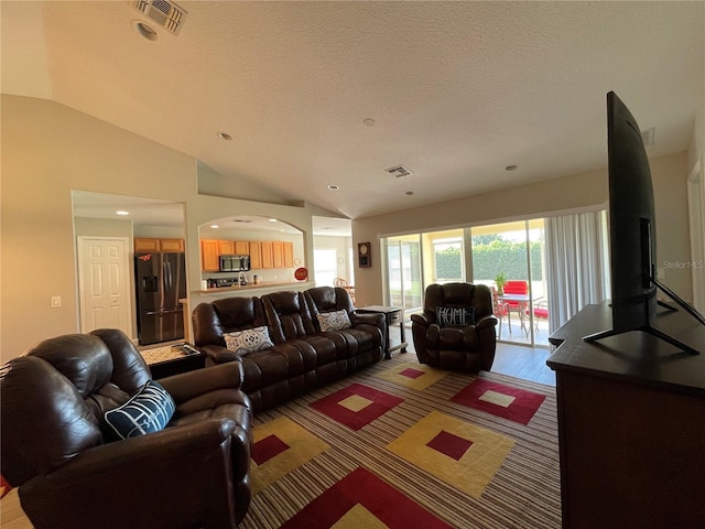 living room with wood-type flooring, a textured ceiling, and vaulted ceiling