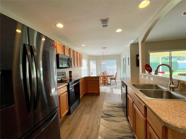 kitchen featuring plenty of natural light, hanging light fixtures, black appliances, and sink