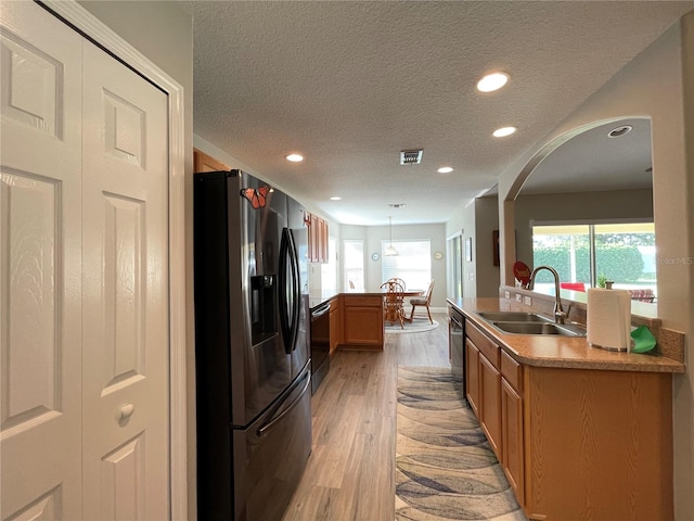 kitchen with light hardwood / wood-style floors, decorative light fixtures, sink, appliances with stainless steel finishes, and a textured ceiling