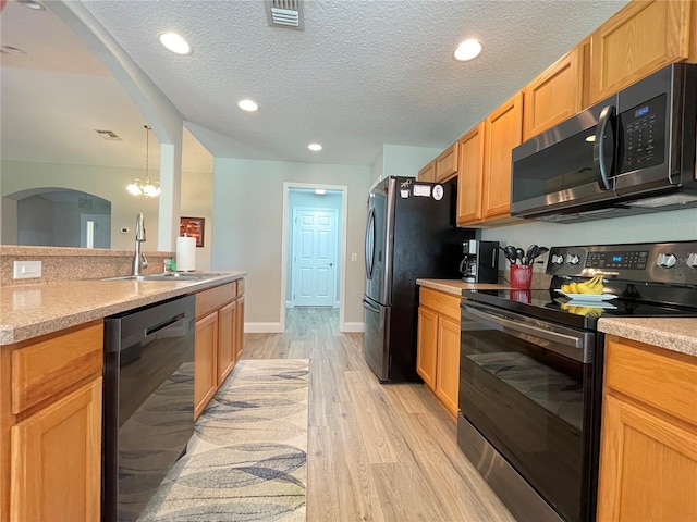 kitchen featuring sink, decorative light fixtures, appliances with stainless steel finishes, a notable chandelier, and light wood-type flooring