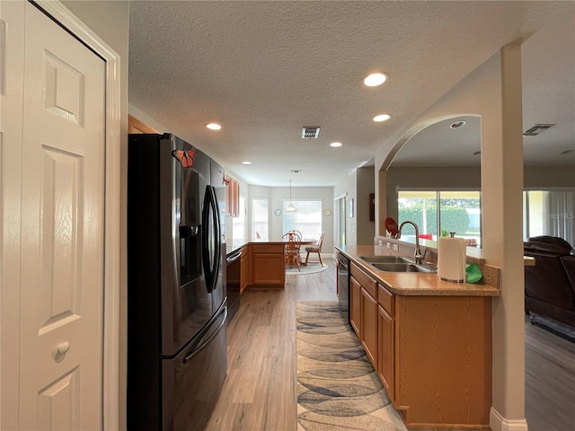 kitchen featuring light wood-type flooring, sink, stainless steel appliances, kitchen peninsula, and a textured ceiling