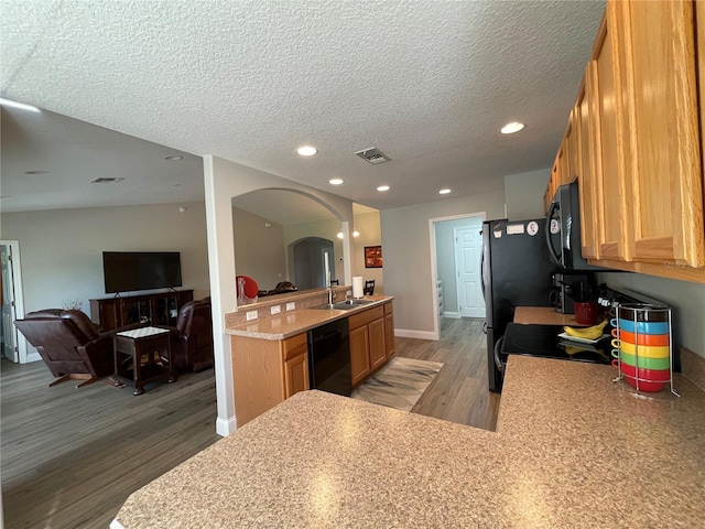 kitchen with sink, kitchen peninsula, dark hardwood / wood-style floors, black appliances, and a textured ceiling