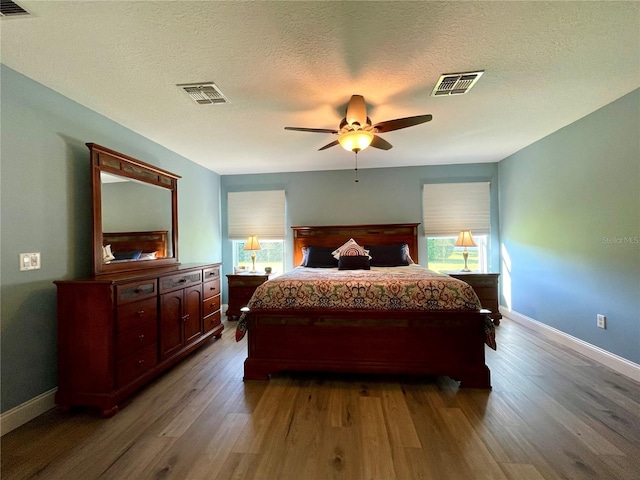 bedroom with wood-type flooring, multiple windows, a textured ceiling, and ceiling fan