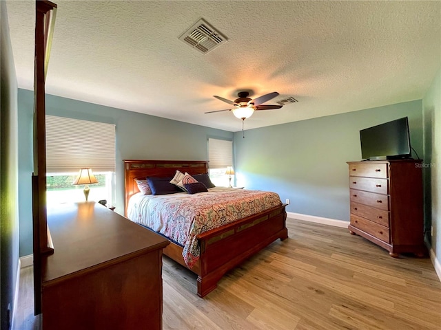 bedroom featuring a textured ceiling, light wood-type flooring, and ceiling fan