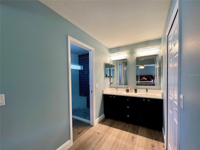 bathroom featuring a tile shower, vanity, hardwood / wood-style floors, and a textured ceiling