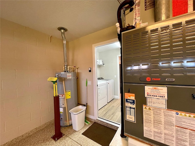 utility room featuring water heater, washer and clothes dryer, and heating unit