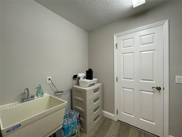 laundry area with light hardwood / wood-style flooring, sink, and a textured ceiling