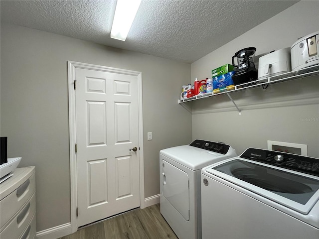 washroom with washing machine and dryer, dark hardwood / wood-style floors, and a textured ceiling