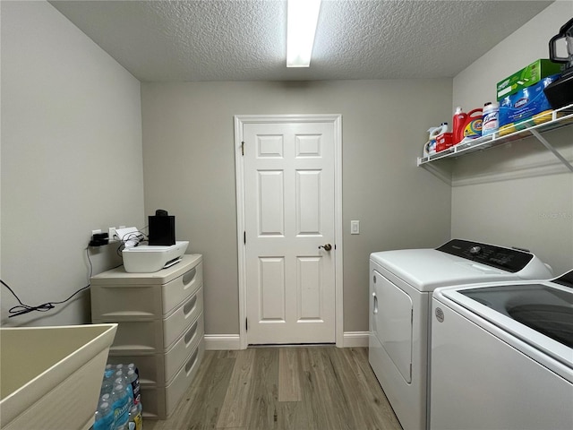 laundry room featuring a textured ceiling, light wood-type flooring, and independent washer and dryer