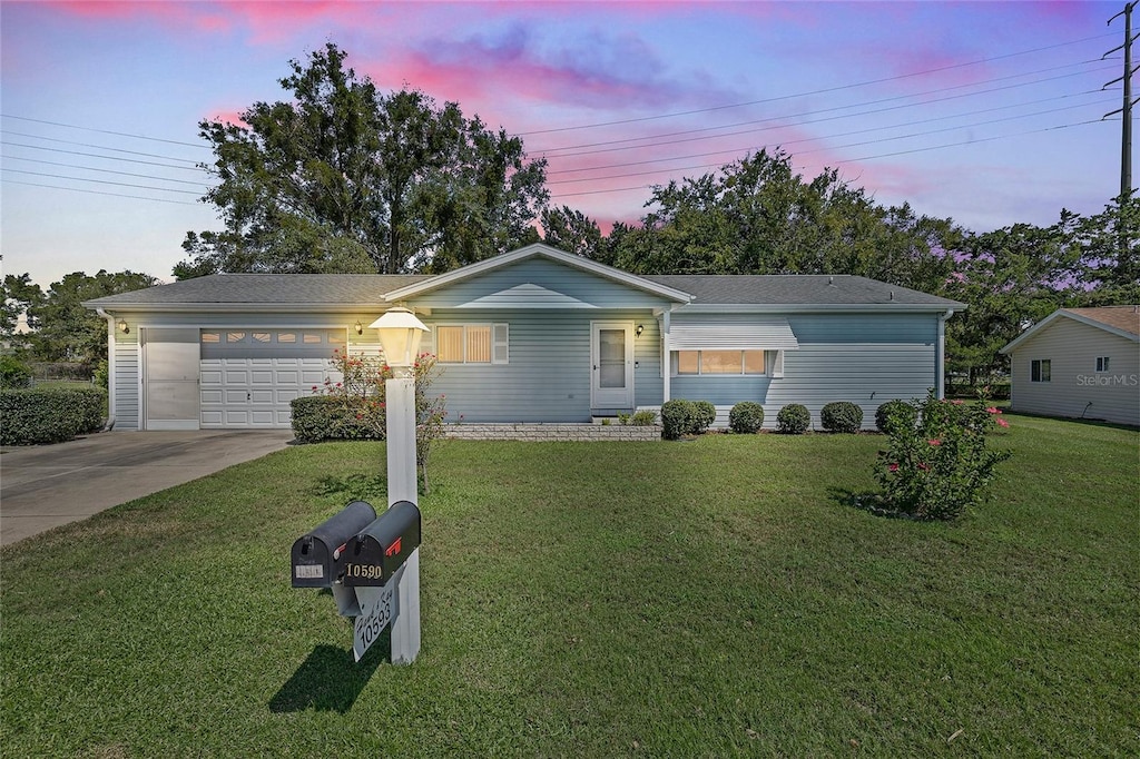 ranch-style house with driveway, a garage, and a front lawn