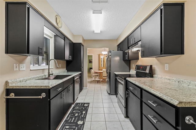 kitchen featuring under cabinet range hood, dark cabinets, stainless steel appliances, and a sink