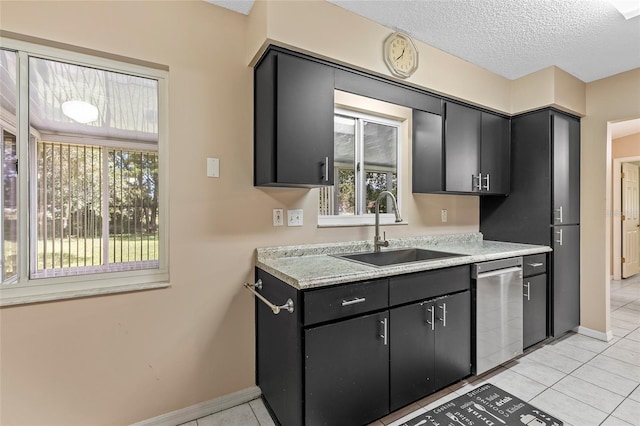 kitchen featuring a textured ceiling, light tile patterned flooring, a sink, light countertops, and dishwasher