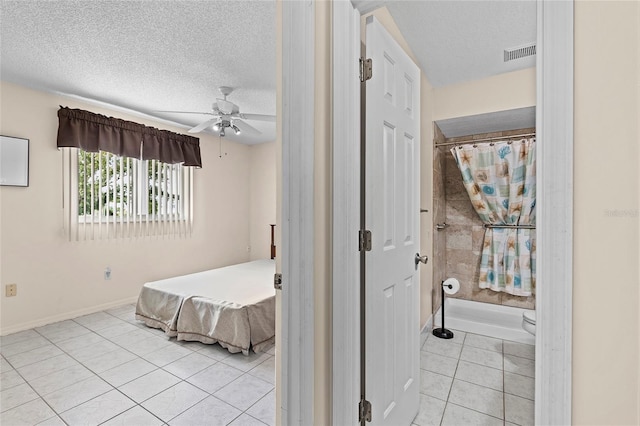 bedroom with light tile patterned floors, a textured ceiling, visible vents, and baseboards