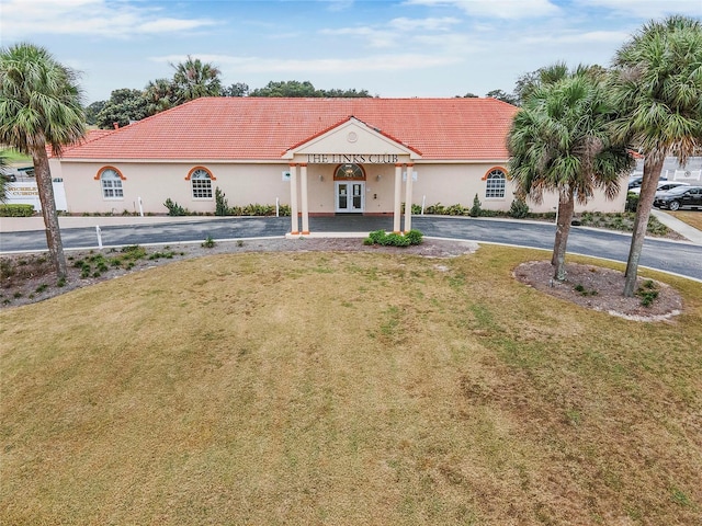 mediterranean / spanish house with a front yard, a tile roof, driveway, and stucco siding