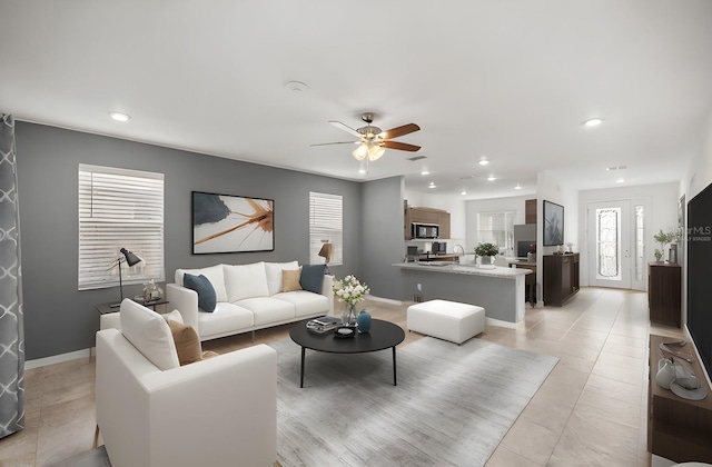 tiled living room with ceiling fan and sink