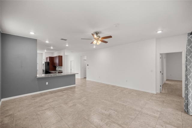 unfurnished living room featuring ceiling fan and sink