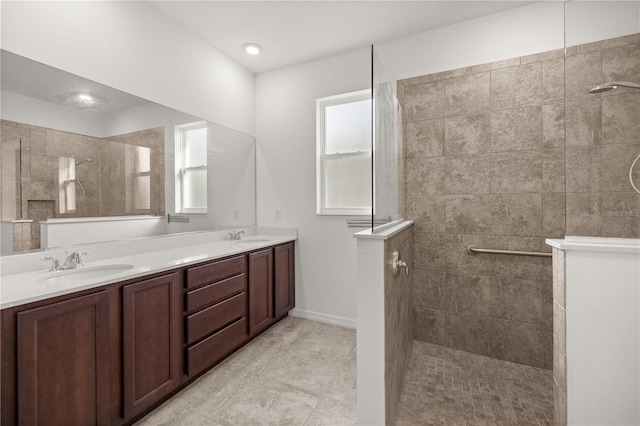 bathroom with a wealth of natural light, vanity, and tiled shower