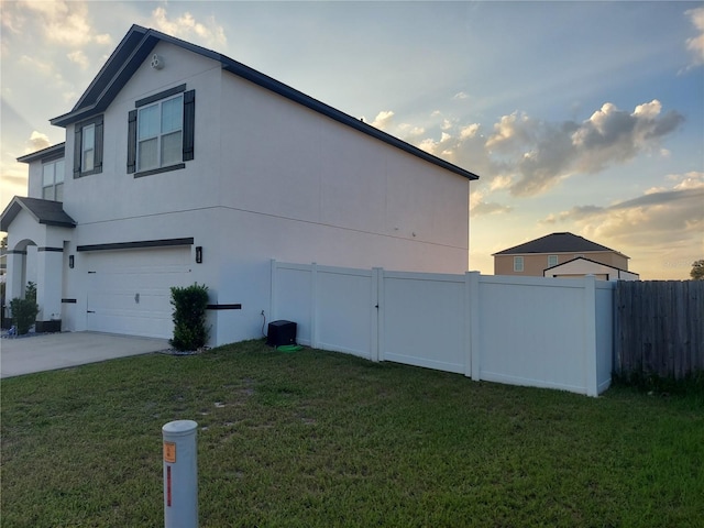 property exterior at dusk with a lawn and a garage