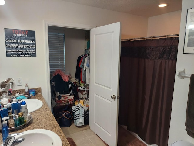 bathroom with walk in shower, vanity, and tile patterned floors