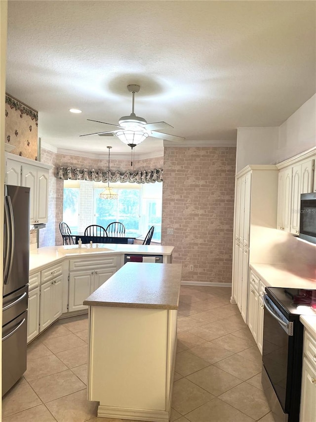 kitchen featuring ceiling fan, pendant lighting, brick wall, appliances with stainless steel finishes, and a center island