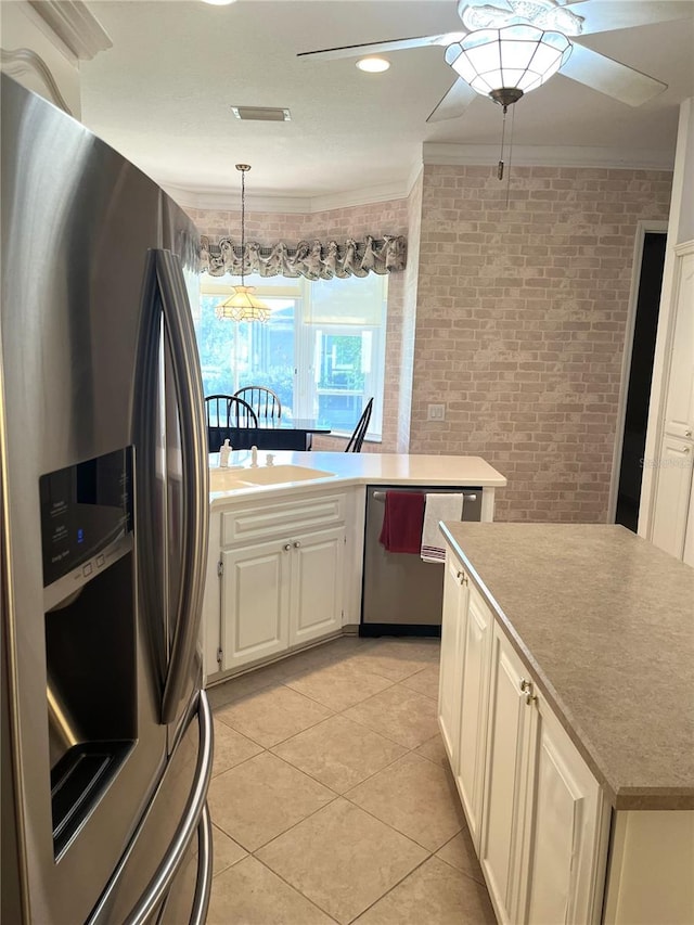 kitchen with appliances with stainless steel finishes, ceiling fan with notable chandelier, light tile patterned floors, crown molding, and decorative light fixtures